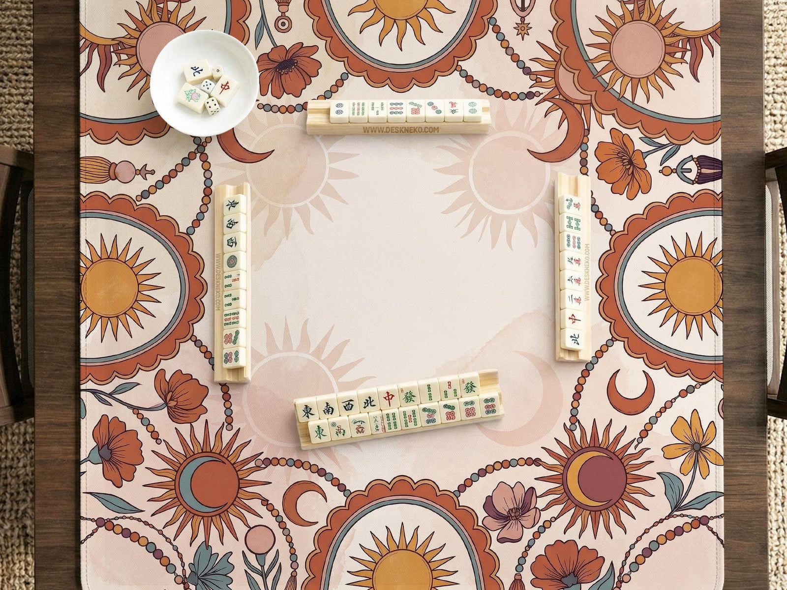 A square terracotta mahjong mat with suns, crescent moons, and floral accents around a patterned border and open center.