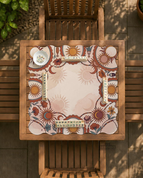 A square mahjong mat with a scalloped edge, sun and moon artwork, terracotta flowers, a soft cream background, and a decorative border around the play area.
