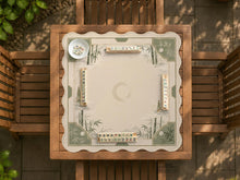 Square mahjong mat with a sage green bamboo and mountain design, cream center, scalloped border details, and gold line accents.