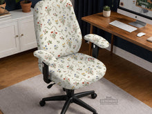 Cream chair cover with a scattered cottage garden floral print in red, blue, yellow, and green on a light background.