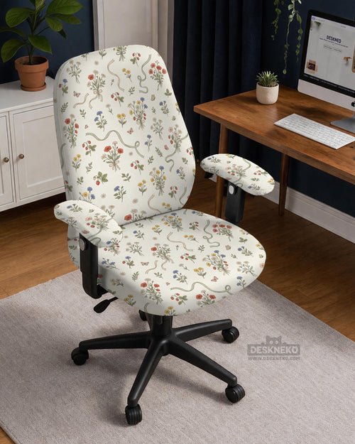 Cream chair cover with a scattered cottage garden floral print in red, blue, yellow, and green on a light background.