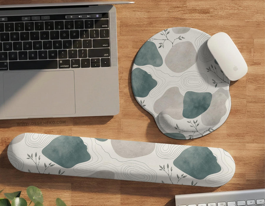 Sage green ergonomic mousepad and keyboard wrist rest with abstract shapes, soft gray details, cream space, topographic contour lines, and leafy branch accents.