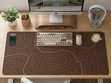Brown desk mat with a repeating topographic contour line pattern in a neutral earth tone design.