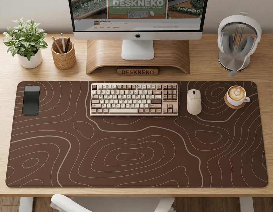 Brown desk mat with a repeating topographic contour line pattern in a neutral earth tone design.