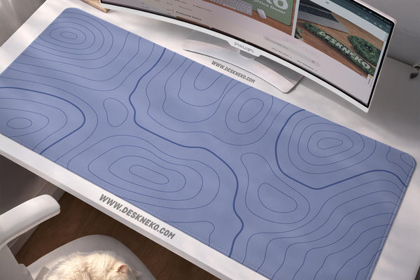 A periwinkle deskmat with thin blue contour lines printed across the surface.