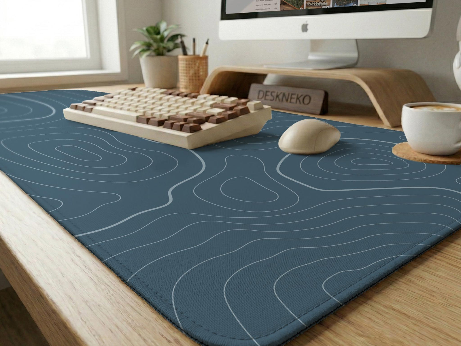 A slate blue desk mat with thin contour line map art on a light background.