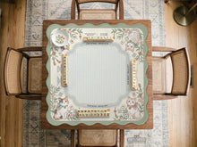 Square pastel mahjong mat with a cat illustration, blue stripes, cream background, floral corner details, and printed rules around the edge.