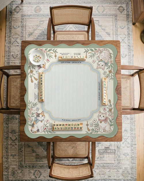 Square pastel mahjong mat with a cat illustration, blue stripes, cream background, floral corner details, and printed rules around the edge.