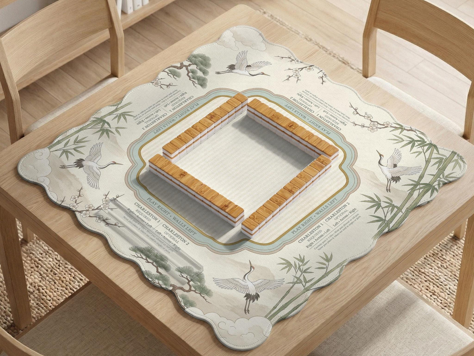 Sage green scalloped mahjong mat with bamboo, crane, and blossom illustration and printed rules around the border.