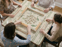 Sage green mahjong mat with a bamboo garden design, koi fish, crane birds, ginkgo leaves, and a cream background.