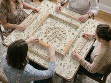 Cream mahjong mat with a delicate meadow flower pattern, soft beige background, and muted sage green leaves.
