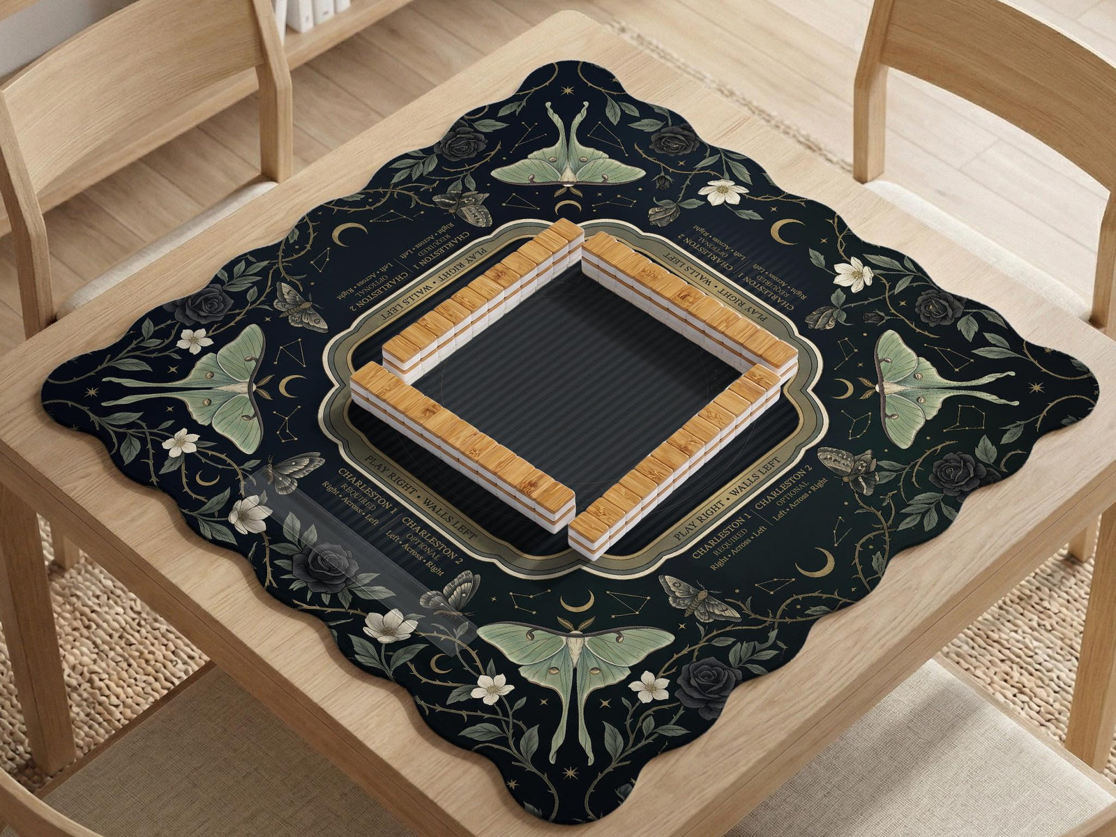 A dark floral mahjong mat with a scalloped edge, moth and flower artwork, and an American Mahjong rules layout on a dark background.