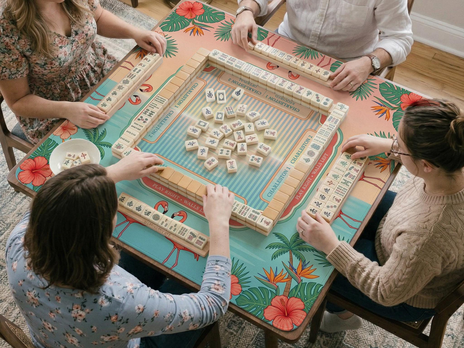 Pink mahjong mat with flamingos, palm leaves, hibiscus flowers, and aqua tropical background.