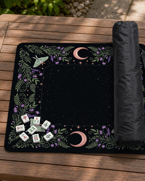 Black mahjong mat with luna moths, purple flowers, curling green vines, and a central play area with a purple border.