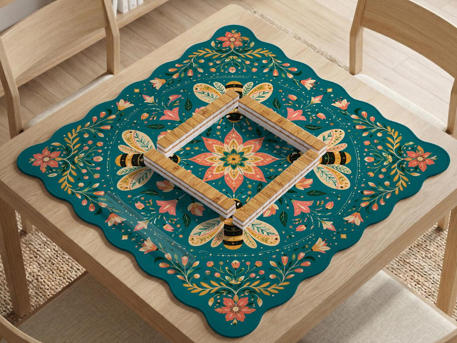 Teal square mahjong mat with a floral border, bee illustrations, and gold accent details on a decorative table surface.