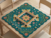Teal square mahjong mat with a floral border, bee illustrations, and gold accent details on a decorative table surface.