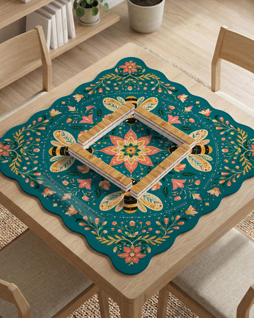 Teal square mahjong mat with a floral border, bee illustrations, and gold accent details on a decorative table surface.