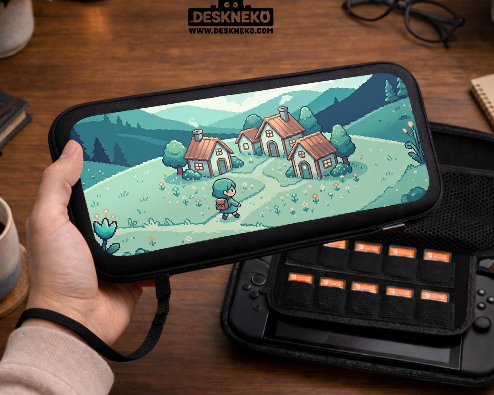 Teal hard shell Switch travel case with pixel art houses, mountains, and a small village scene in green and blue tones.