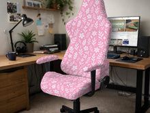 Soft pink floral chair cover shown on a gaming chair with a high back and armrests.