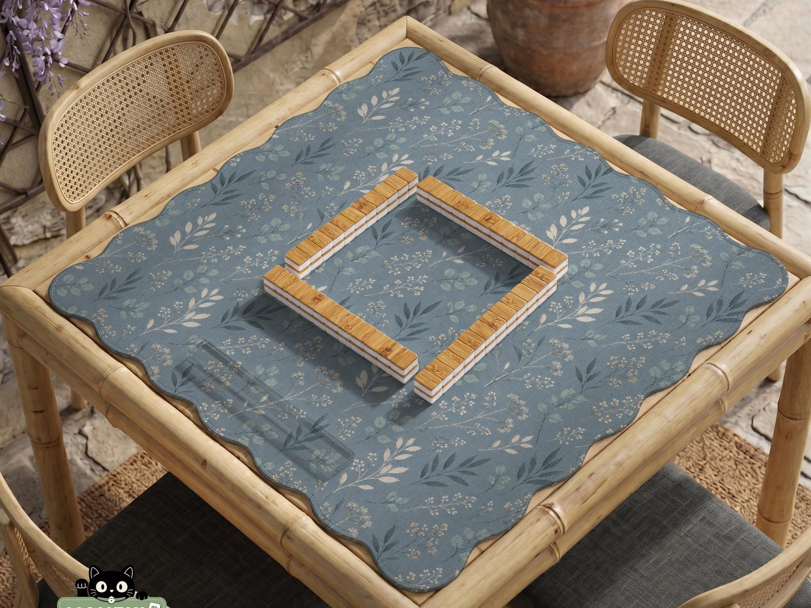 Blue mahjong mat with a botanical floral pattern, pale leaves, and delicate stems on a dusty blue background.