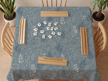 Blue mahjong mat with a dusty linen-look background and small leafy botanical stems in a floral pattern.