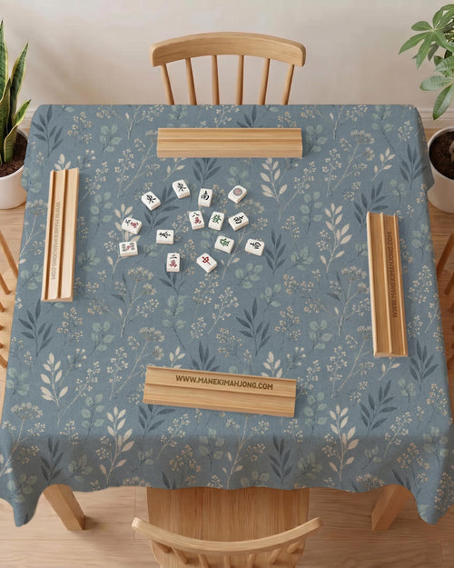Blue mahjong mat with a dusty linen-look background and small leafy botanical stems in a floral pattern.