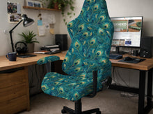 A blue green chair cover with a peacock feather design shown on an office chair with armrests.
