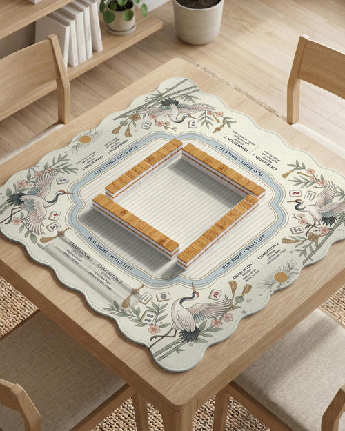 Beige square mahjong mat with a sage border, crane birds, bamboo, flowers, tile icons, and printed rules around a clean center play area.