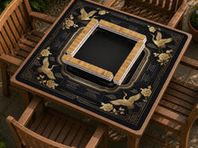 Black mahjong mat with gold crane and floral border artwork and small rule text around the edges.