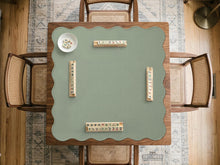 A square sage green mahjong mat with scalloped edges on a plain background.