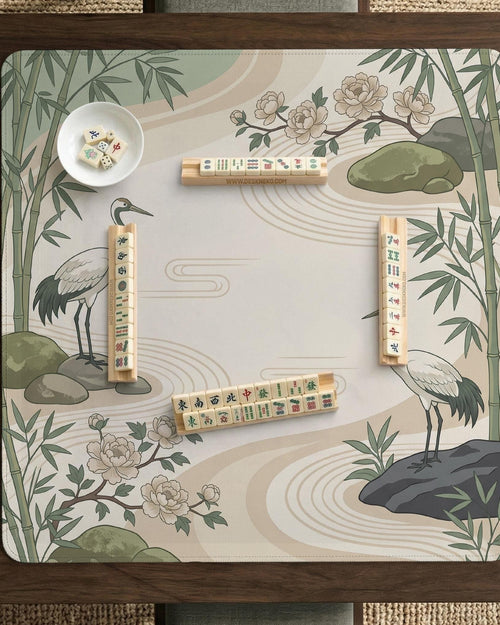 Square mahjong mat with a cream background, sage green cranes, bamboo leaves, peony branches, stones, and thin linework.