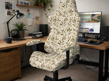 A neutral botanical print chair cover shown on a high back gaming-style office chair with armrests.