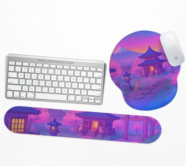 Ergonomic mouse pad and matching keyboard wrist rest printed with a purple twilight Japanese shrine scene with foxes, cherry blossoms and Mount Fuji, shown with a keyboard