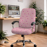 Pink chair cover with a pattern of moons, stars, bows, and small decorative shapes on a chair with armrests.