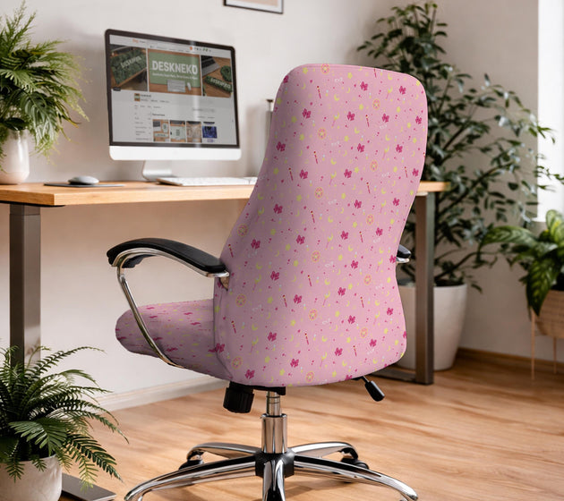 Pink chair cover with a pattern of moons, stars, bows, and small decorative shapes on a chair with armrests.