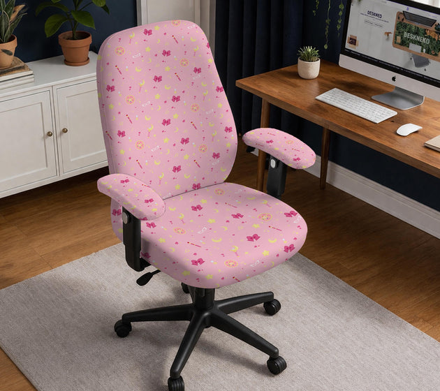 Pink chair cover with a pattern of moons, stars, bows, and small decorative shapes on a chair with armrests.