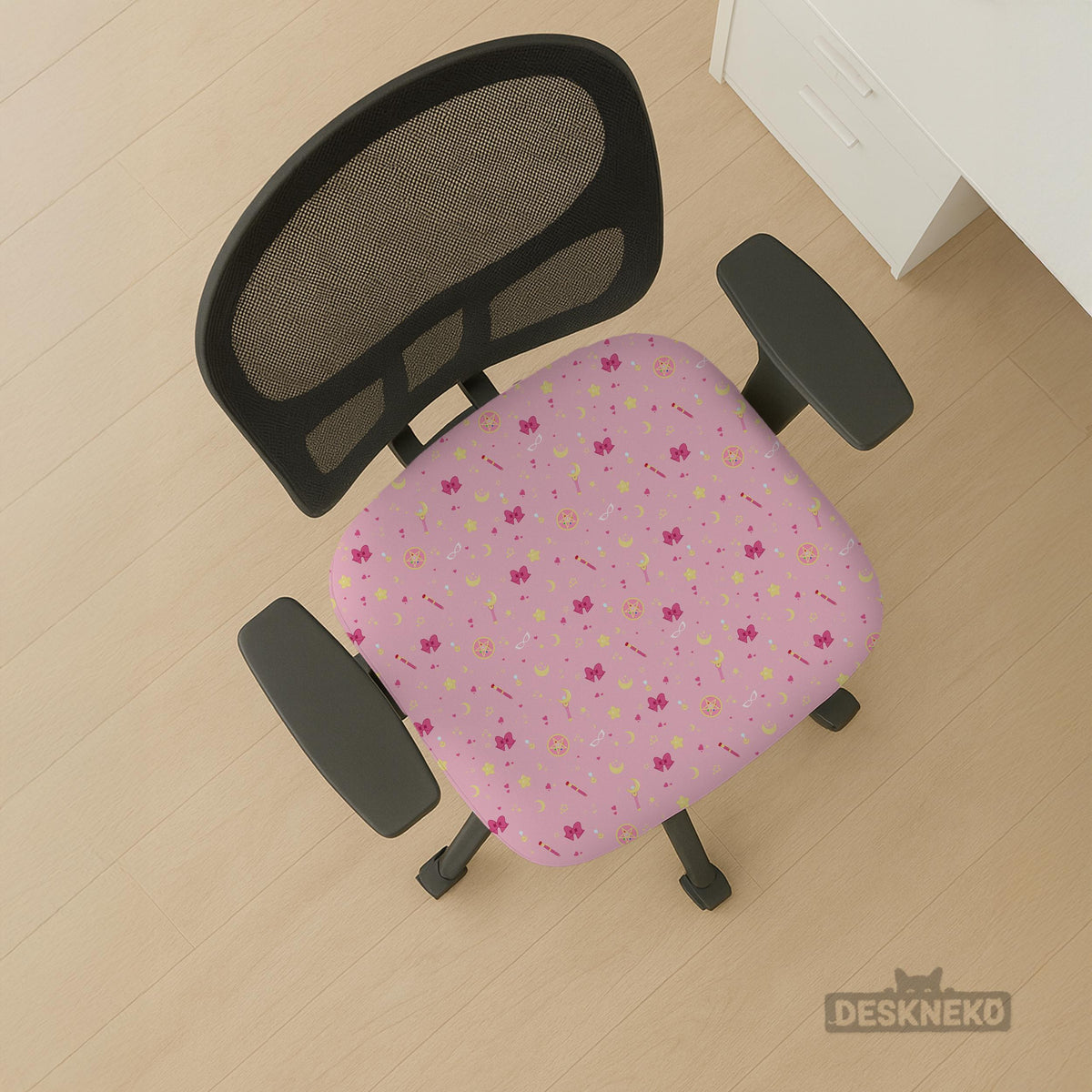 Pink chair cover with a pattern of moons, stars, bows, and small decorative shapes on a chair with armrests.