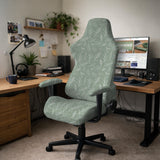 Office chair cover in muted sage green with a light leaf pattern on a white background.
