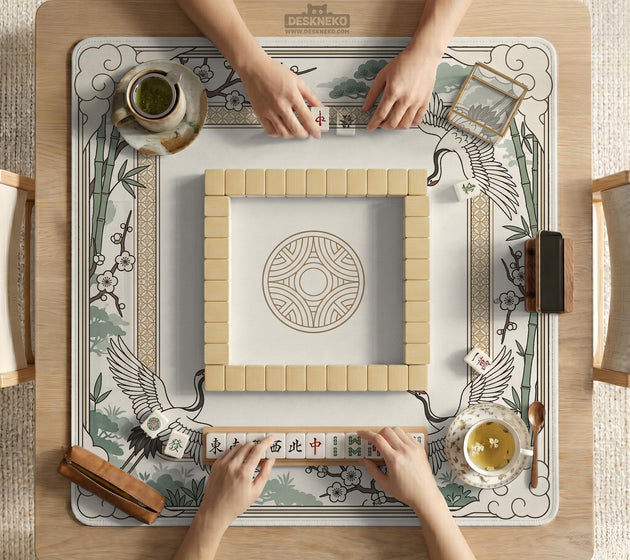 Square mahjong table mat with a cream center and a border design of cranes, bamboo, plum blossoms, and a geometric frame in sage green and warm gold.
