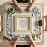 Square mahjong table mat with a cream center and a border design of cranes, bamboo, plum blossoms, and a geometric frame in sage green and warm gold.