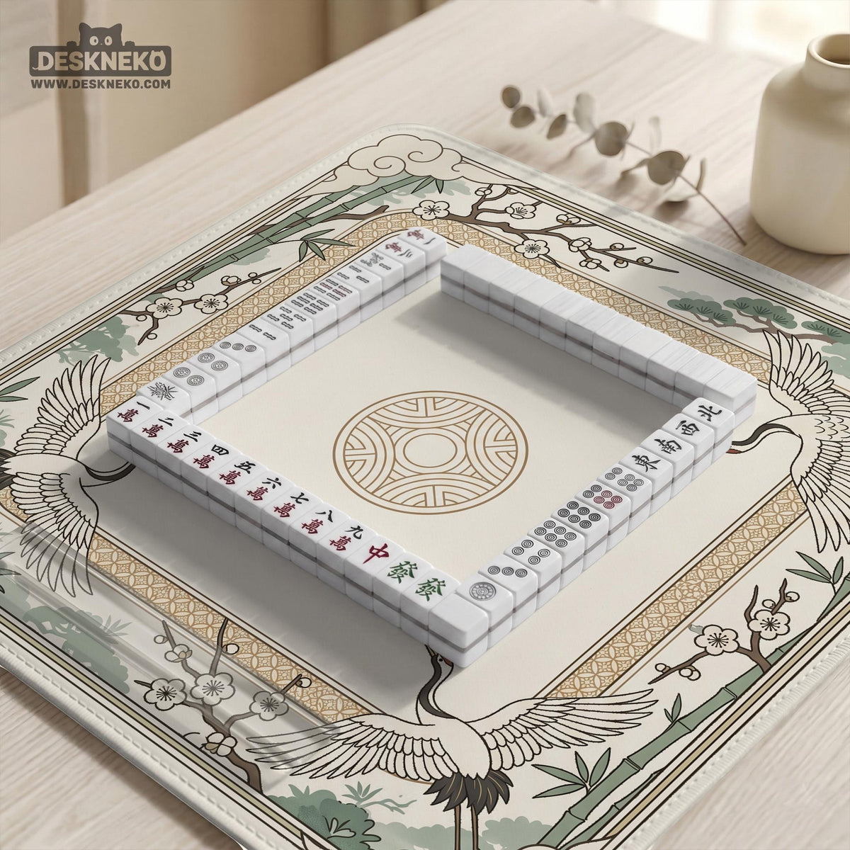 Square mahjong table mat with a cream center and a border design of cranes, bamboo, plum blossoms, and a geometric frame in sage green and warm gold.