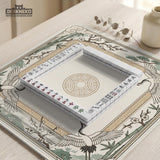 Square mahjong table mat with a cream center and a border design of cranes, bamboo, plum blossoms, and a geometric frame in sage green and warm gold.