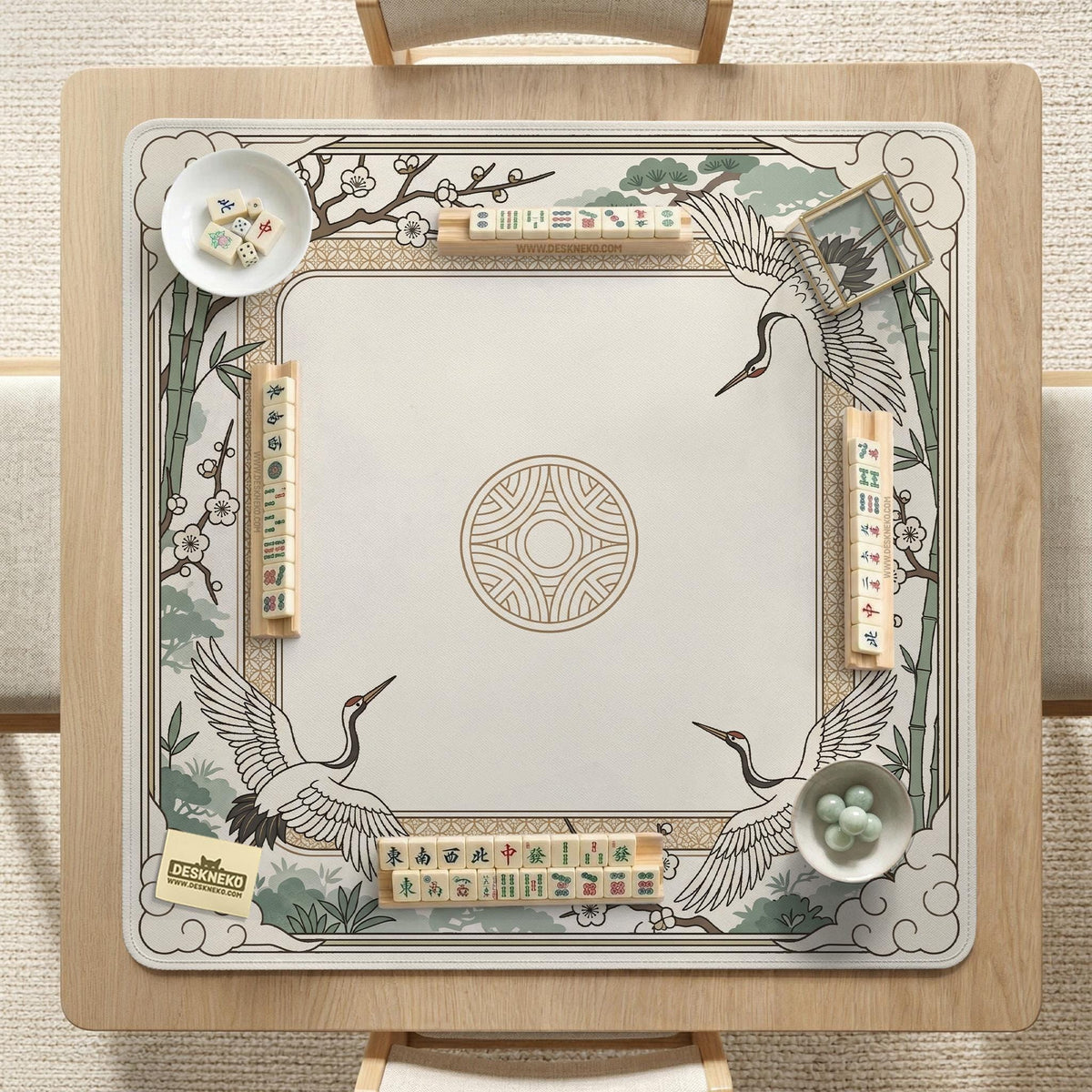 Square mahjong table mat with a cream center and a border design of cranes, bamboo, plum blossoms, and a geometric frame in sage green and warm gold.