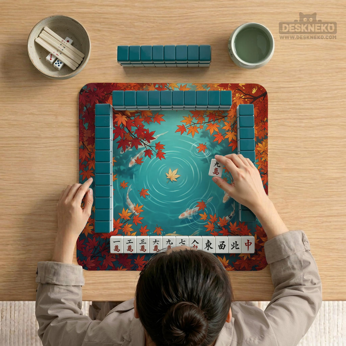 Square teal mahjong mat with koi fish, falling autumn leaves, and pond water artwork.