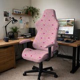 Pink chair cover with a pattern of moons, stars, bows, and small decorative shapes on a chair with armrests.