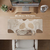 Beige desk mat with fine botanical line drawings and soft abstract shapes on a light neutral background.