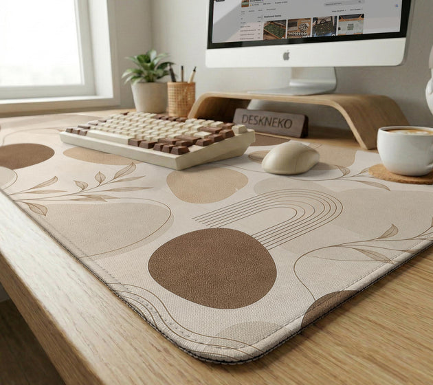 Beige desk mat with fine botanical line drawings and soft abstract shapes on a light neutral background.