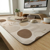 Beige desk mat with fine botanical line drawings and soft abstract shapes on a light neutral background.