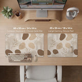 Beige desk mat with fine botanical line drawings and soft abstract shapes on a light neutral background.