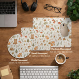 Cream desk mat with a woodland animal pattern featuring foxes, bunnies, mushrooms, berries, acorns, and sage leaves in soft green tones.